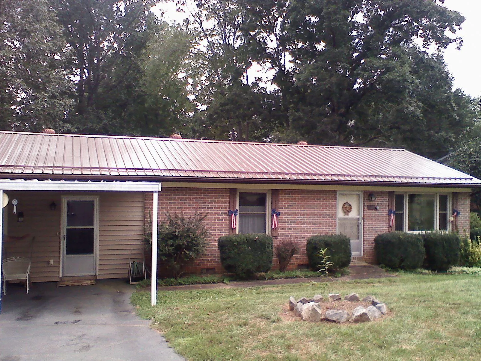 Bronze metal roof and carport on a brick ranch home — Roof Repair work by our crew in Forest City